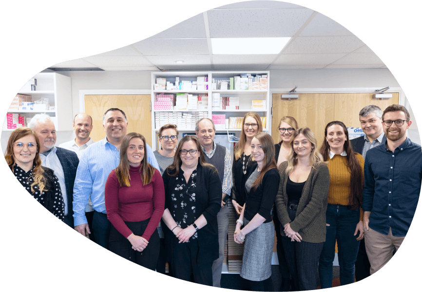 The Independent Pharmacy team gathered in front of a large bookcase, all smiling at the camera